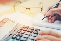 A woman in business clothing sits at a desk looking at tax forms
